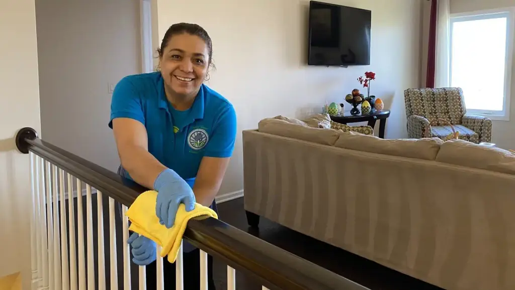 A Touch of Europe cleaner in gloves hand-wiping a wooden stair rail