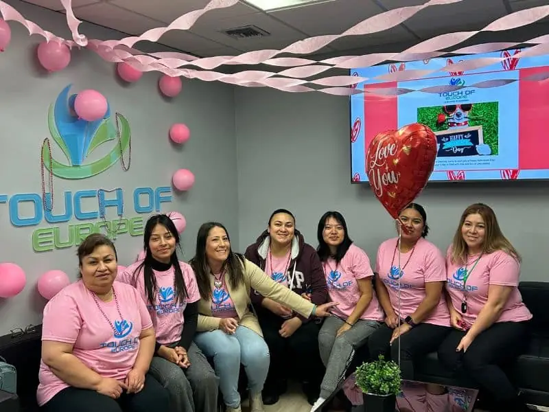Pink-shirt Touch of Europe team in the Odana Road office with pink balloons